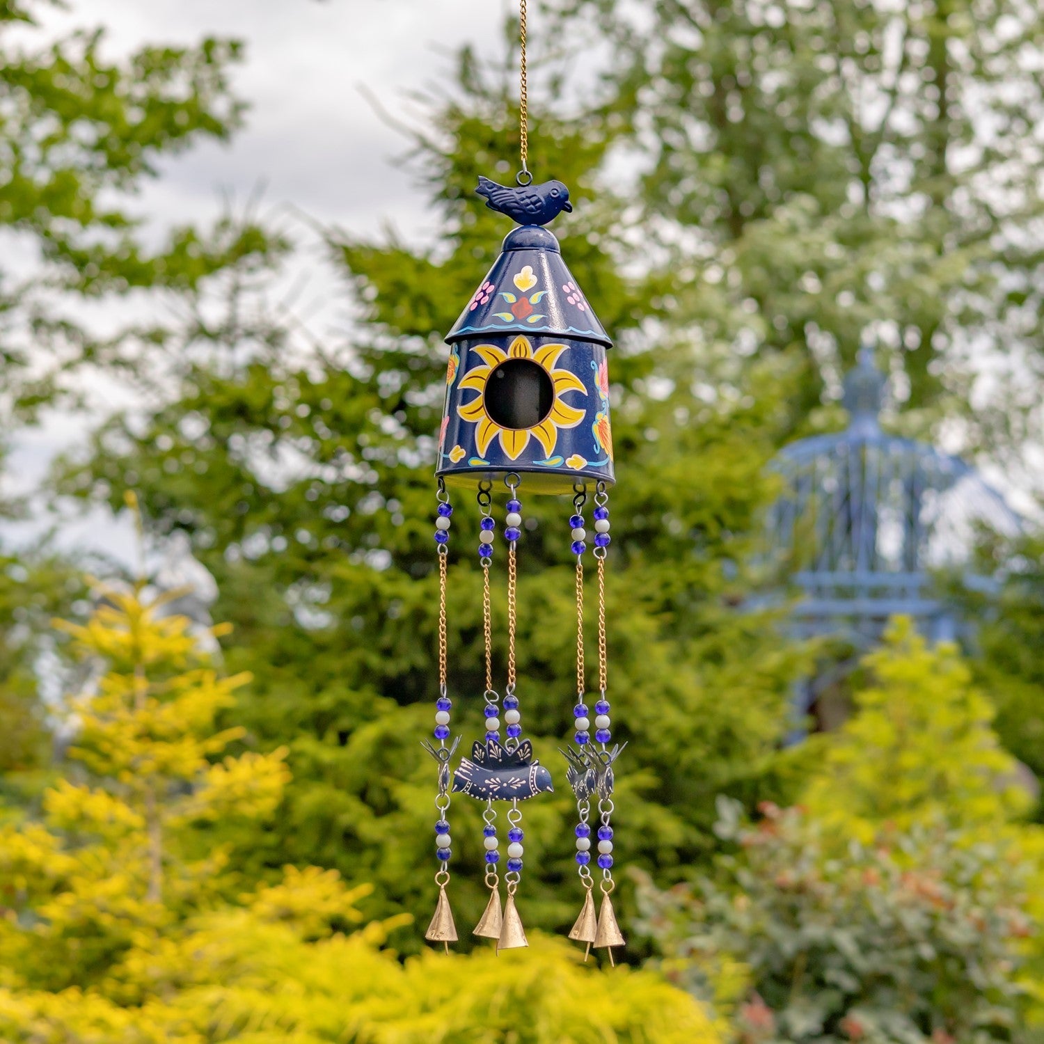 Decorative wind chime with sunflower design against a blurred garden background