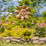 Decorative sun-shaped wind chime with hanging bells against a garden background