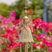 Decorative angel with a bell hanging against a blurred floral background