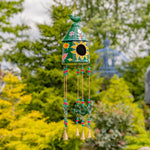 Decorative wind chime with birdhouse design hanging in a garden
