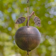 Decorative metal wind chime with hanging leaves against a blurred natural background