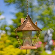 Decorative hanging lantern with a house design against a blurred natural background