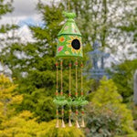 Decorative wind chime with a birdhouse design in a garden setting