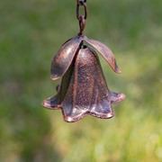 Bronze bell-shaped object on a blurred green background