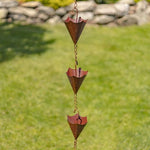 Copper rain chain with decorative elements on a grassy background