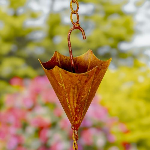 Rust-colored metal rain chain with a blurred garden background