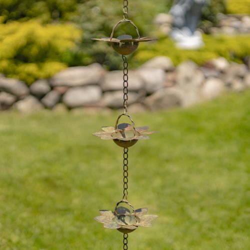 Decorative metal wind chime hanging outdoors with a garden background