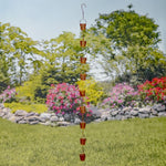 Decorative hanging rain chain with a garden and flowers in the background